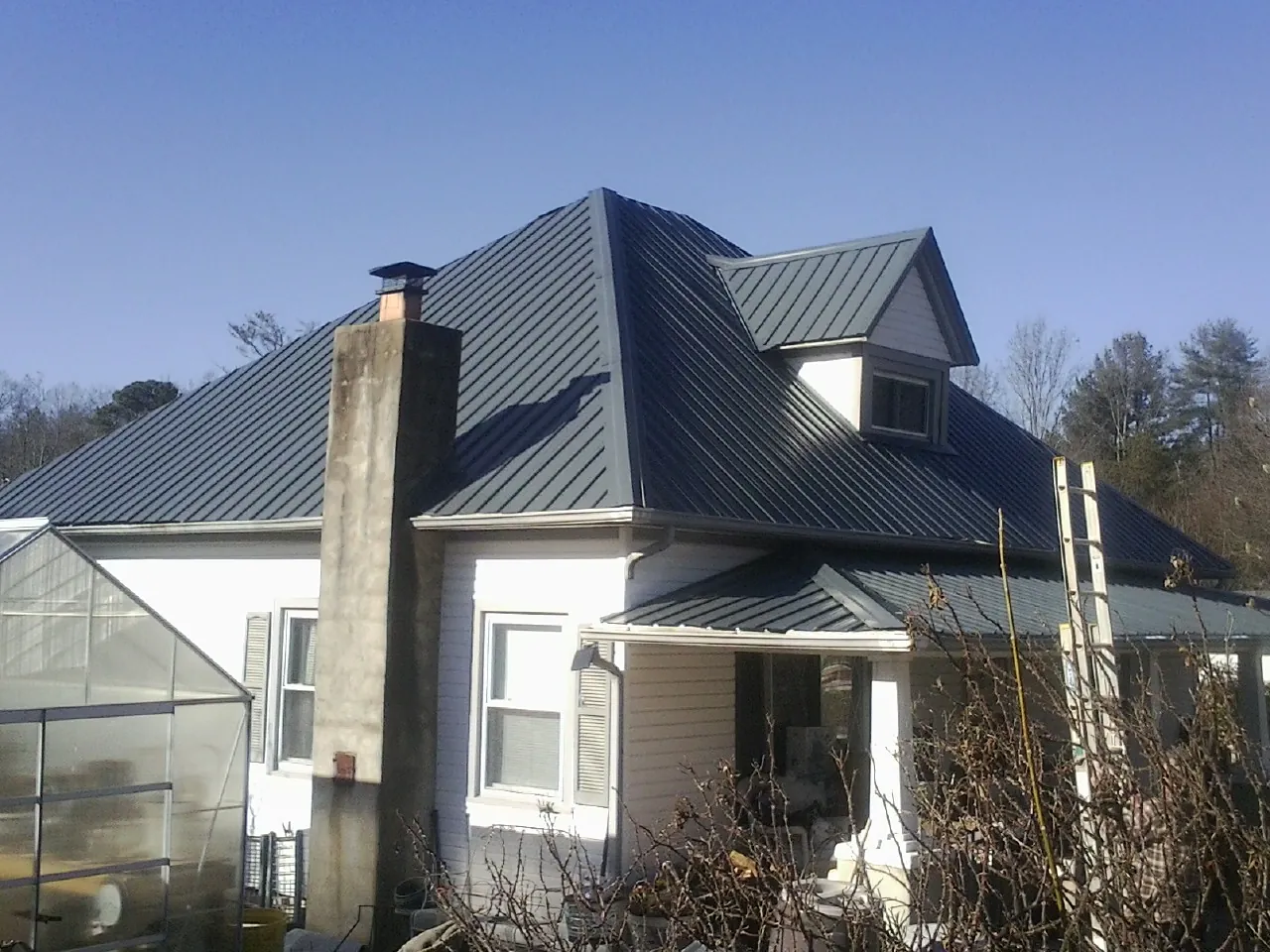 Dark blue standing seam metal roof on a white farmhouse with dormer — Slate & Tile Roof Repair by Roofing Brothers in Marlboro