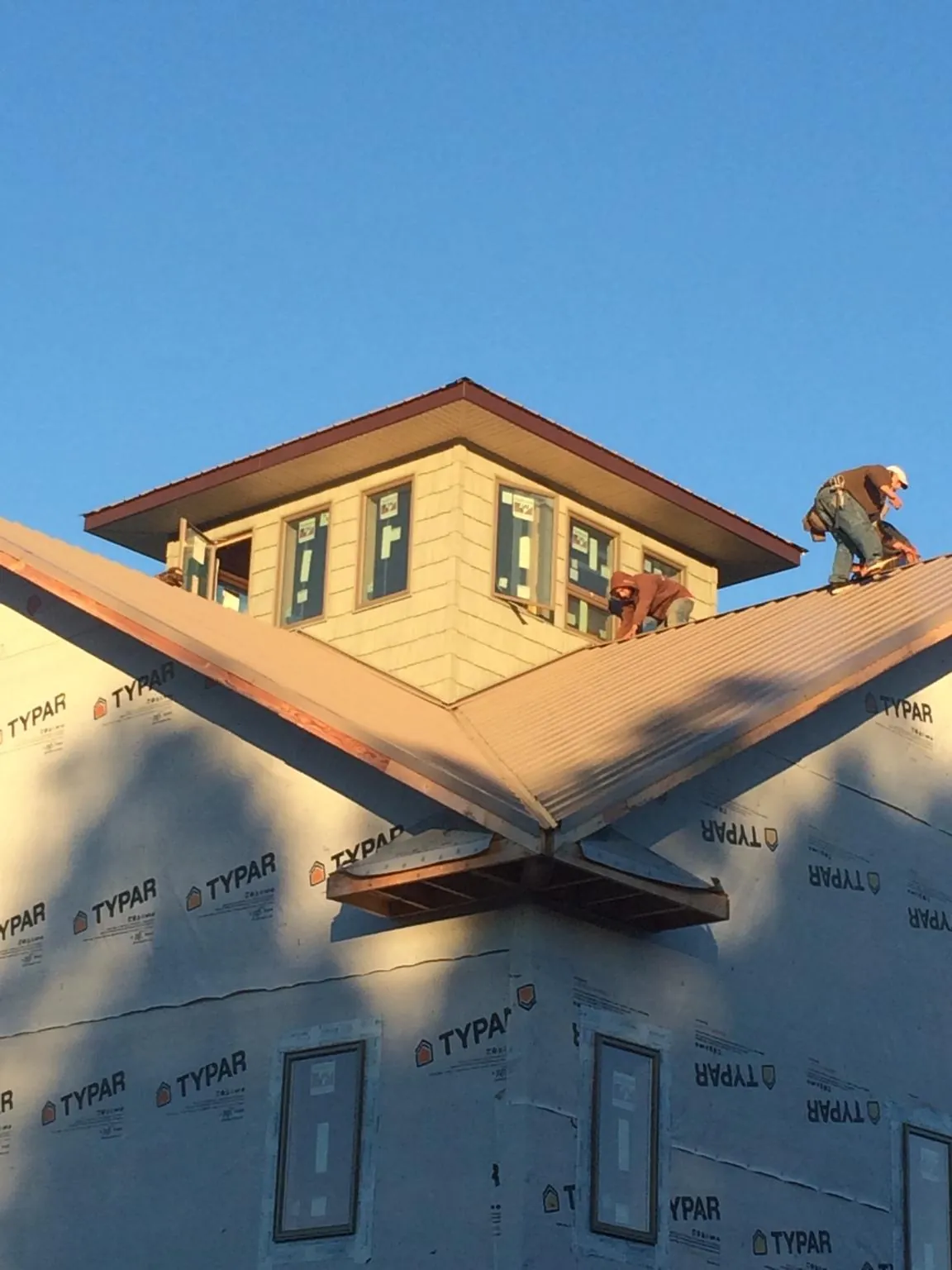 Roofers working around a rooftop cupola on a new metal roof at sunset — Roof Waterproofing in Marlboro by Roofing Brothers